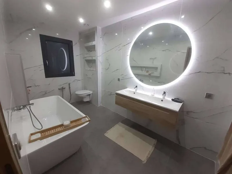 Salle de bains réalisée par Chauffeo : baignoire îlot, vasque et miroir lumineux